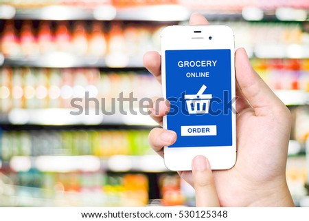 Hand holding smart phone with add to cart words on screen over blur supermarket background, e-commerce, business and technology concept