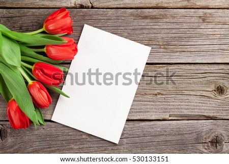 Red tulips and Valentine's day greeting card on wooden table. View with copy space