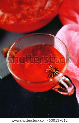 Cranberry herbal hot tea drink in glass teapot with cinnamon and star anise spice on black backdrop