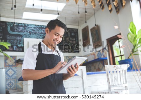 portrait of asian young male cafe owner with tablet Royalty-Free Stock Photo #530145274