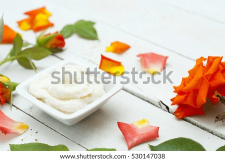 cosmetic cream and rose flowers, petals on white wooden table background