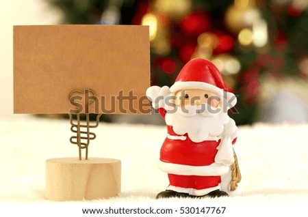 Closed up Santa Clause and the message on the photo holder with the background of blurred Christmas trees