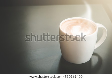 Latte coffee cup on black wood table in cafe selective focus(Vintage tone)