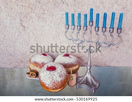 Jewish menorah with candles and sweet donuts are traditional symbols for Hanukkah holiday
