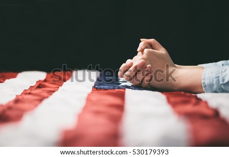 Hands praying over USA flag Royalty-Free Stock Photo #530179393