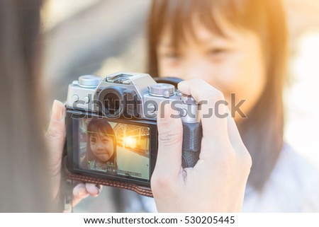 Little girl taking picture using a digital camera: flare light