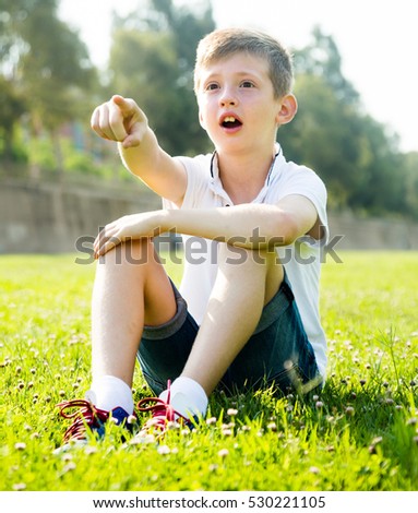 russian boy sitting grass surprise pointing away