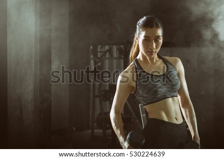 Toned picture,Asian fitness girl with perfect shape body workout lifting a dumbbell in the gym, Exercising with dumbbells.