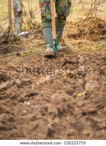 Man digging with spade in autumn or spring garden,