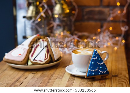 Christmas gingerbread cookie fir tree and cup of coffee at yellow festive lights background