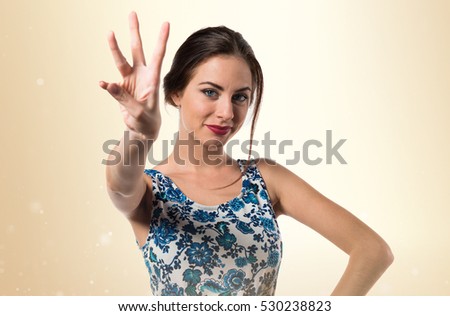 Pretty young girl counting three on ocher background