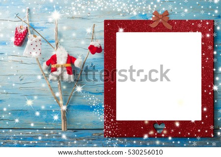 Christmas photo frame card, Santa claus clothes hanging in a tree  and empty photo frame with heart, blue wooden background