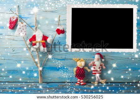 Christmas photo frame card, Tree, Santa Claus and reindeer rag dolls and vintage empty photo frame on blue wooden background