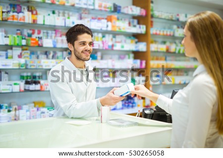 Experienced pharmacist counseling female customer in modern pharmacy Royalty-Free Stock Photo #530265058