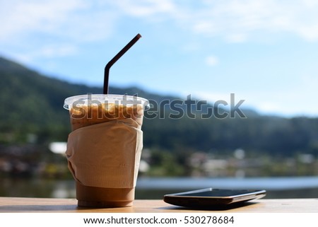 Ice coffee with smart-phone in the sunny day ,relaxing time on the cafe near the lake view in Ban Rak Thai,Mae Hong Son, Northern of Thailand