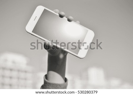 Black and white image of child hand holding smart phone. closeup view