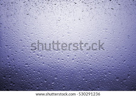 Drops of rain on a window glass with very diffuse landscape purplish blue color