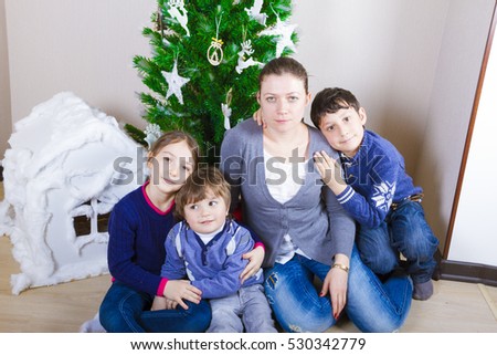 Family with three children around a Christmas tree at home