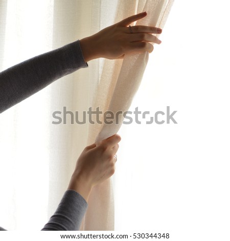 Woman opening curtains in living room