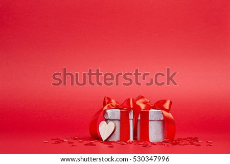 Red background with silver gifts, heart and confetti 