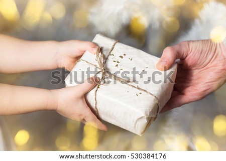 Christmas present, father and daughter, hands holding white gift , selective focus.