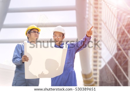 Architect and foreman construction worker discussing about new project and looking at blueprint, one of them pointing a new location 