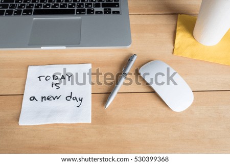Laptop with paper cup, mouse, pen and napkin with message on wooden desk. Morning workspace in office