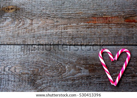 Candy canes as heart on wooden background. As a symbol of the day Saint Valentine's or Christmas.