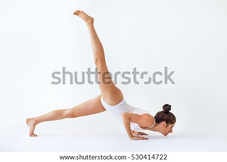Young woman doing yoga asana Trianga Dandasana. Staff pose with right leg up
