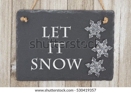 Old fashion Christmas message, A retro chalkboard with snowflakes hanging on weathered wood background with text Let it Snow