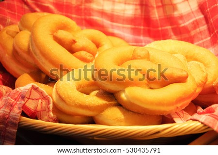 Sweet pretzel donuts on checkered towel in wicker basket. Toned photo.