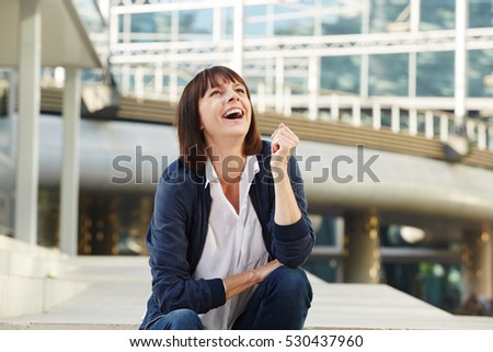 Portrait of laughing older woman sitting outside in city