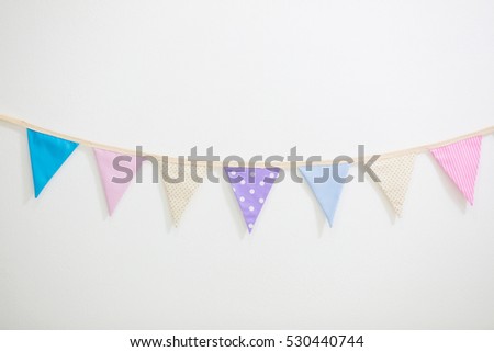 Colorful Party flags bunting hanging on white wall for holiday decoration
