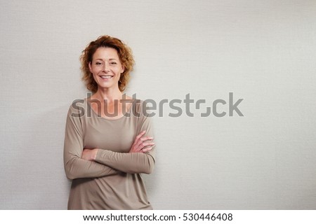 Portrait of older woman smiling with arms crossed by wall Royalty-Free Stock Photo #530446408