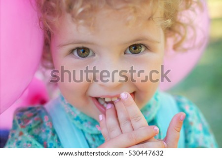 Image of  sweet and funny baby girl with balloons, closeup portrait of child, cute toddler with amazed smiling face. Two years old