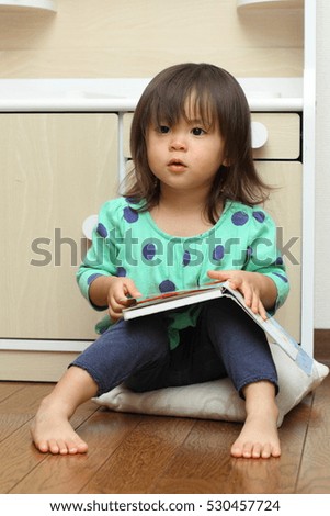Japanese girl reading a picture book (1 year old)