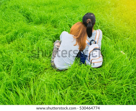 women sitting on the grass ,Two young women sitting on the grass hugging Rear view.
