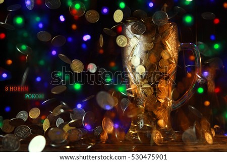 New year congratulation card with glass cup, falling ukraine coins and christmas tree lights on the background with ukrainian text on. Text card translation - happy new year