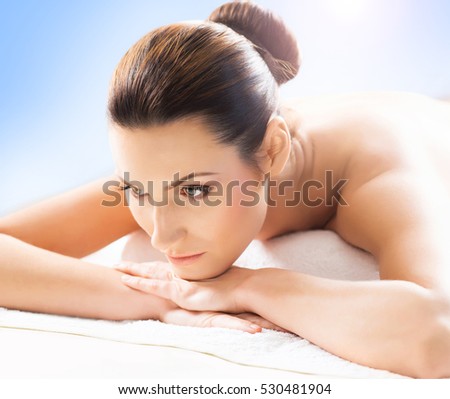 Beautiful, young and healthy woman in spa salon. Massage treatment, traditional medicine and healing concept. Blue background.