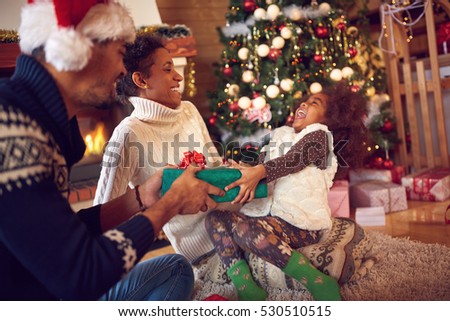 Happy family on Christmas opening gifts sitting on floor at home
