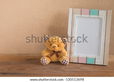 Teddy bear and photo frame on wooden background