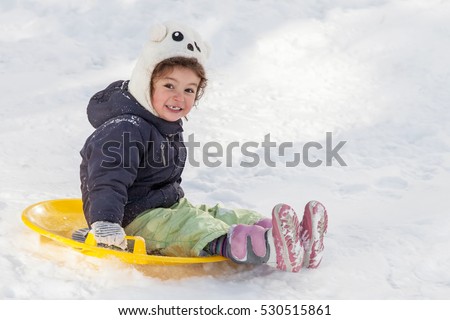 Cute little girl with saucer sleds outdoors on winter day, ride down the hills, winter games and fun
