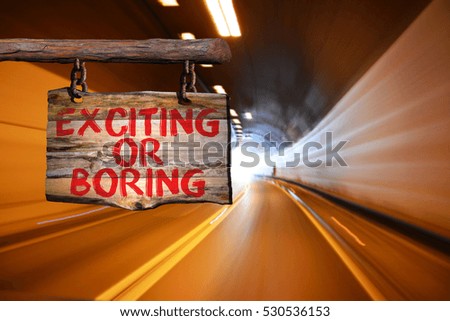 Exciting or boring motivational phrase sign on old wood with blurred background