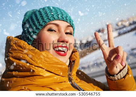 Cold snowy Russian winter. Beautiful girl enjoys snowfall on New Years Eve.