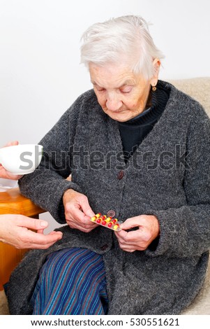Picture of an elderly woman holding her pills while medical check up