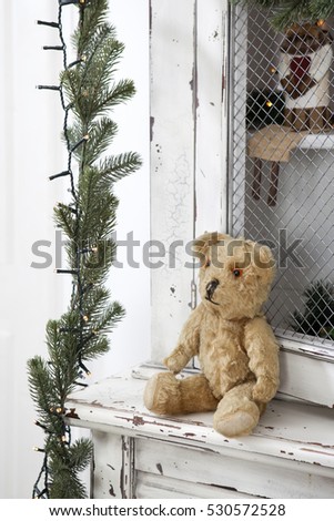 Vintage cupboard with Christmas toys and Christmas tree garland. Vintage teddy-bear sitting on the wardrobe