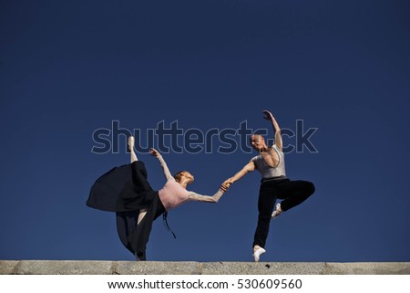 young woman and a man performing gymnastic exercises against the sky