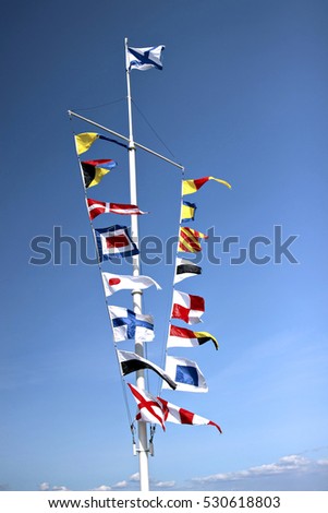 Marine flags of different countries on a mast on blue sky background