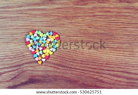 Big heart composed of small multi color hearts on wood background, Love concept