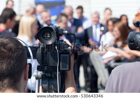 Filming an media event with a video camera. Press conference. Royalty-Free Stock Photo #530643346